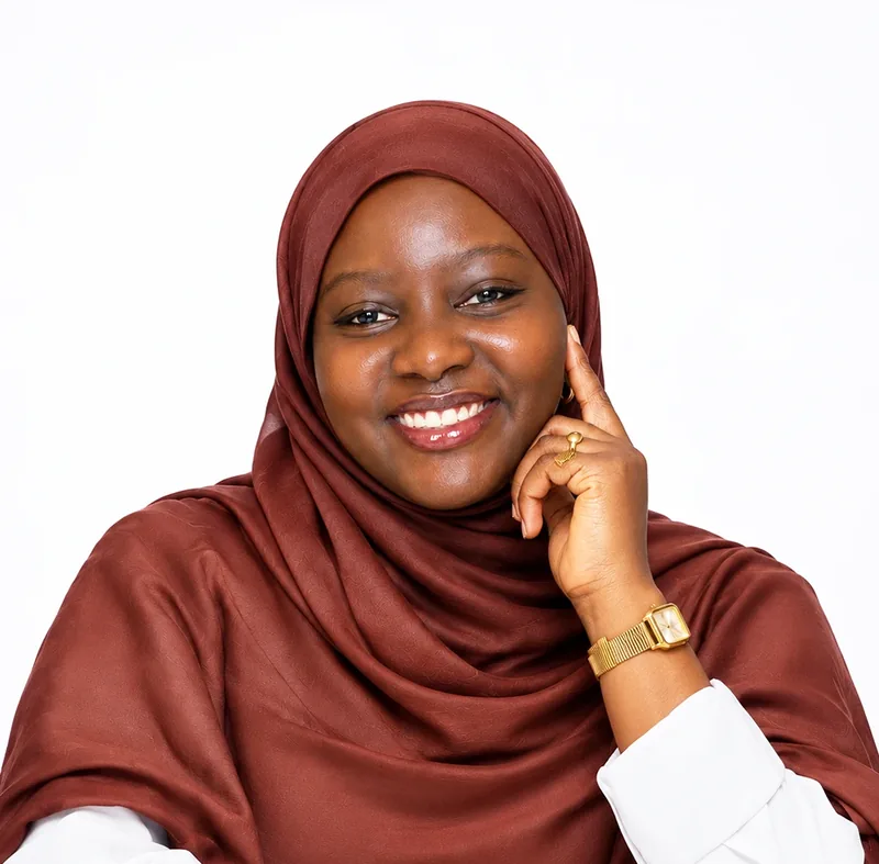 Portrait d'Anna Ndiaye, souriante, en voile bordeaux et chemise blanche.