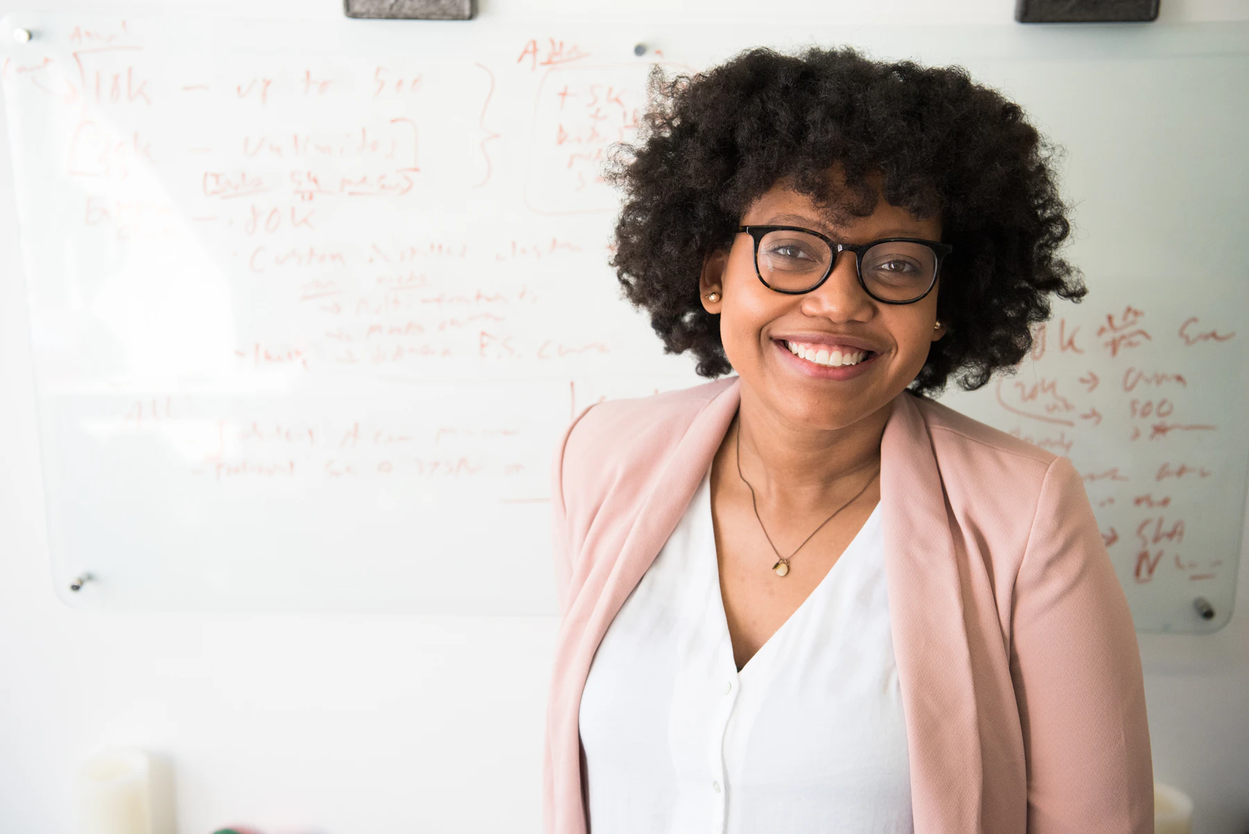 Consultante souriante devant un tableau blanc couvert de notes de stratégie